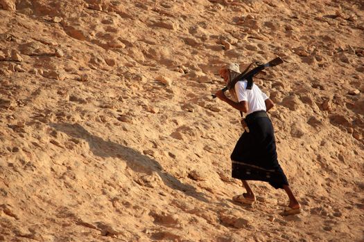 man with a gun walking uphill