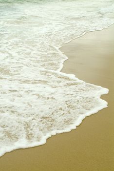 gentle waves breaking on sandy beach on the coast 