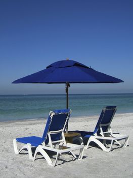 2 sun loungers on the beach by the waters edge with umbrella and table on vacation holiday relax chill sea ocean gulf of mexico usa america florida sand color colour blue green aqua turquoise tranquil peace quiet silence deck chairs sit lie couple two concepts metaphors