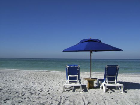 2 sun loungers on the beach by the waters edge with umbrella and table on vacation holiday relax chill sea ocean gulf of mexico usa america florida sand color colour blue green aqua turquoise tranquil peace quiet silence deck chairs sit lie couple two concepts metaphors