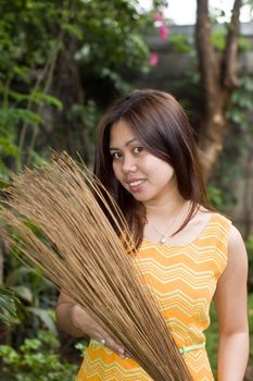 A beautiful lady holding stick broom while cleaning garden