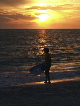 surfer going into the sea at sunset