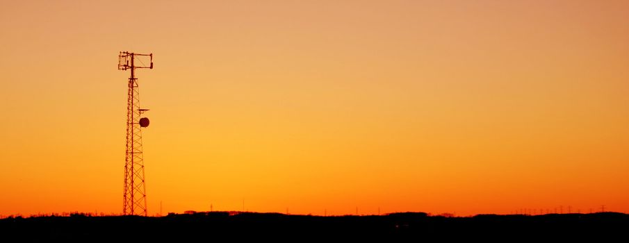 A cell phone tower silhouette in the sunset
