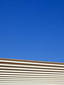 Metal beams from an outdoor structure stretch across a clear blue sky.
