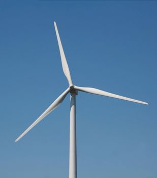 A closeup of a windmill against a blue sky.
