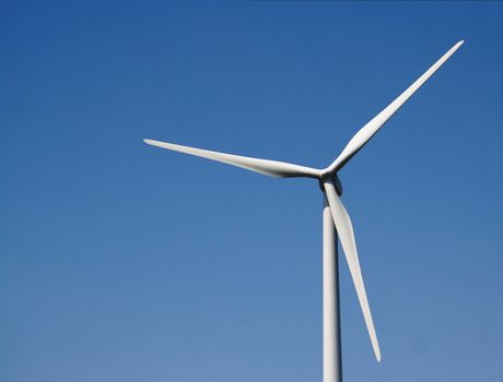 A closeup of a windmill against a blue sky.