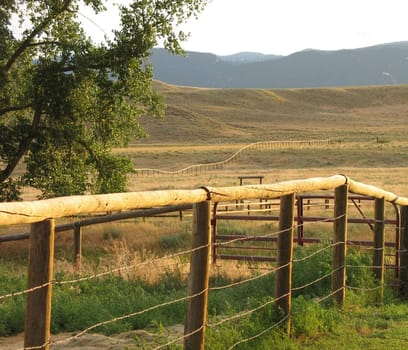 Ranch fence runs into the distance on a Western landscape at sunset.