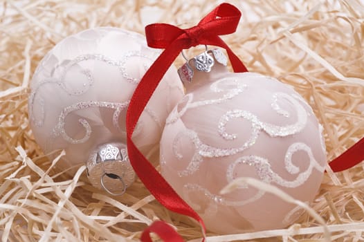 christmas balls with decorative red ribbon on hay as background