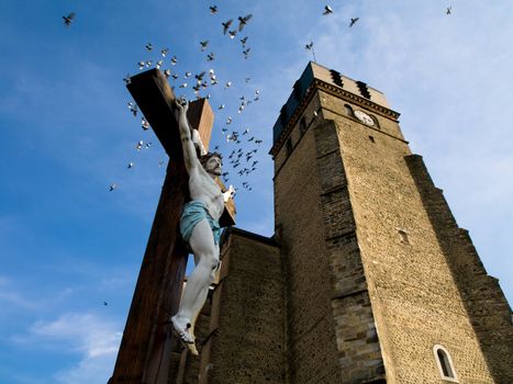 Jesus christ crucifix in front of a Church in France with flying birds