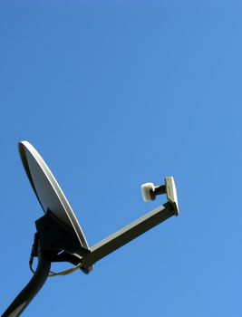 Satellite dish listening against a clear blue sky.