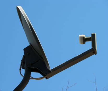 Satellite dish isolated against a clear blue sky.