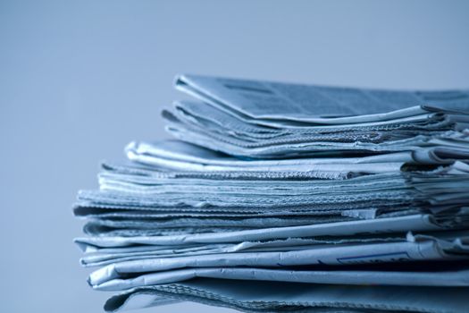 Blue tinted closeup shot of stack of newspapers with shallow depth of field