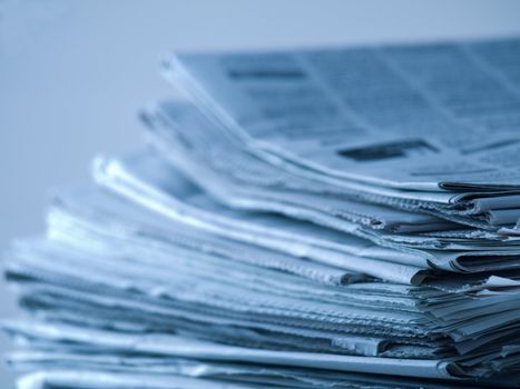 Blue tinted closeup shot of stack of newspapers with shallow depth of field