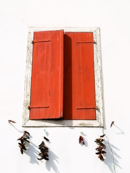 Red wooden window with drying red peppers  in the Basque village of Espelette 