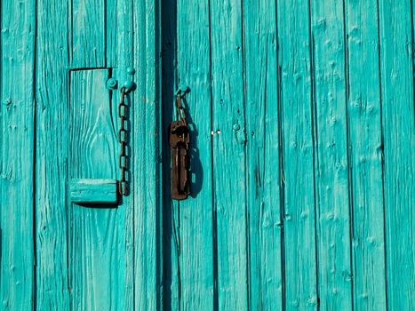 Turquoise wooden entrance door with chain