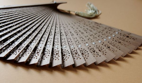 old Chinese hand fan on a light brown background