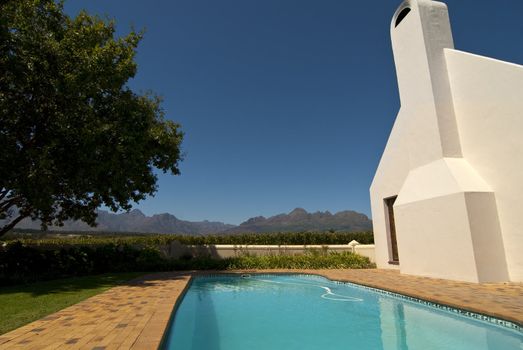 Clean swimming pool with a light building on the side and mountains in the background