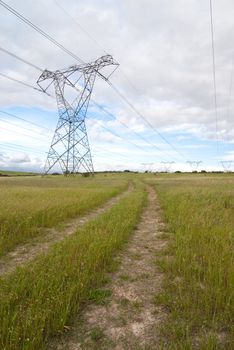 Electricity pylon in a grass field with clouds overhead