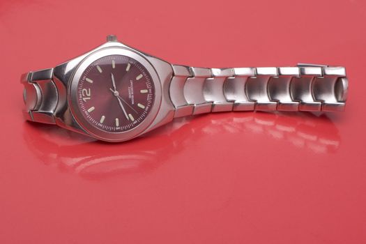 Men sport watch on it's side, reflecting on red surface