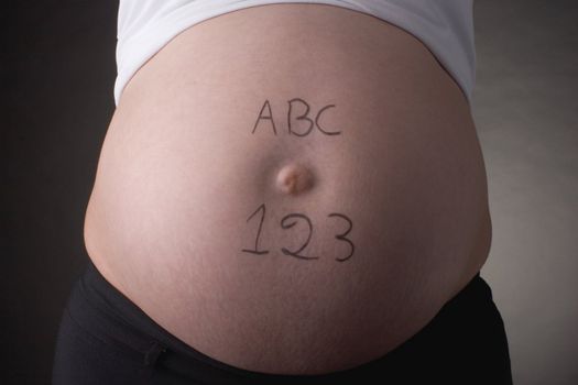 seven month pregnant belly with ABC and 123 written 
