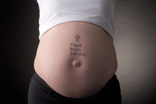 seven month pregnant belly with arrow pointing up and food goes in here written on the stomach