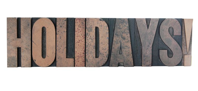 old, ink-stained wood letters spell out the word 'holidays!' in all caps isolated on white