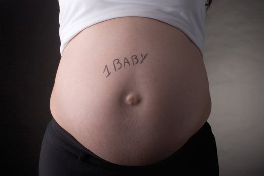 sevent month pregnant belly with 1 baby written on the stomach
