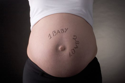 seven month pregnant belly with one baby, two baby written on the stomach