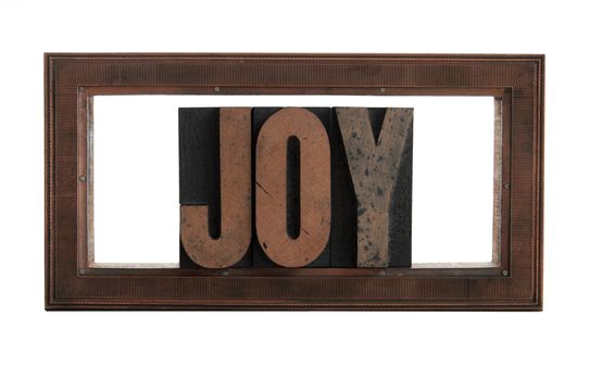 the word 'joy' in a printer's copper frame cut isolated on white