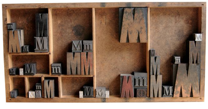 the letter M in upper and lower case and different fonts, both serif and san serif, all in a wood type case