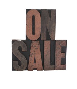 old, ink-stained letterpress wood type letters form the words 'on sale'
