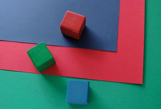 three blocks in red, green and blue on three sheets of red, green and blue paper