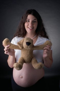 Seven month pregnant women holding stuff toy dog by the arm