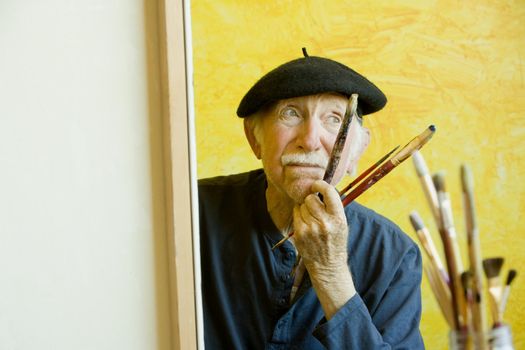 Elderly painter wearing a beret working on a large canvas