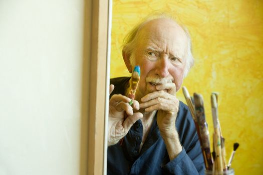 Elderly painter working on a large canvas