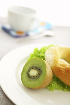 Breakfast on the table ( coffee, kiwi, bagel, salad ) 