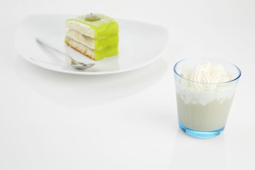 Glass of Frappucino with creamy top and piece of green cake.