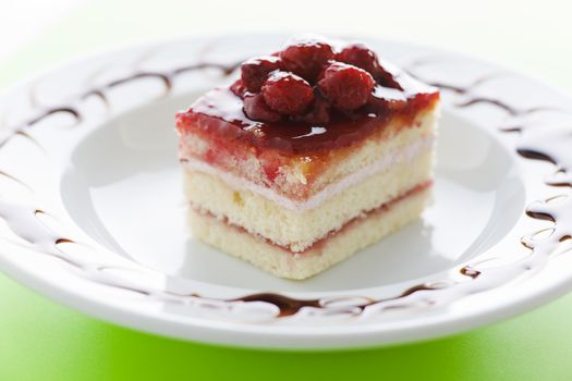 Piece of raspberry cake on the plate with chocolate dressing