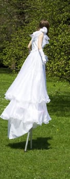 White woman on stilt in green park