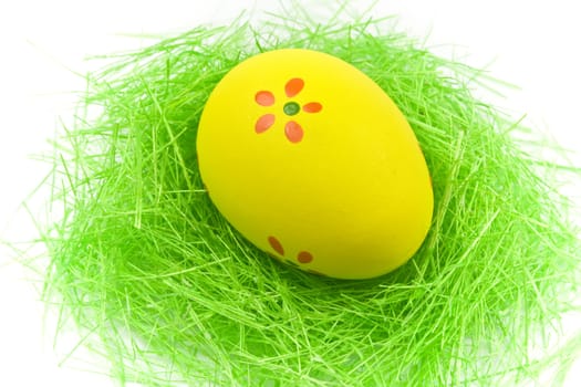 One yellow easter egg with green grass isolated on white