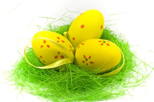 Three yellow easter egge with green grass isolated on white