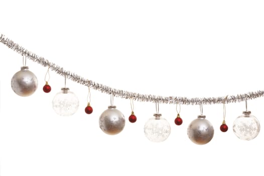 Silver christmas decoration with silver, transparent and red balls over a white background