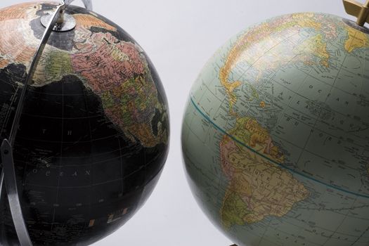 A dark globe showing north america facing a light globe showing south america
