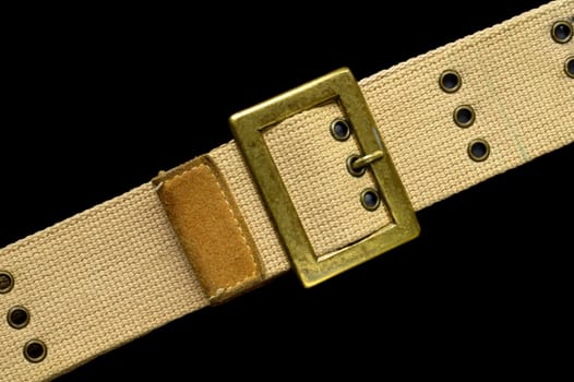 Macro of a brass buckle on a canvas belt, isolated on black. Space for text above and below belt, on black background.