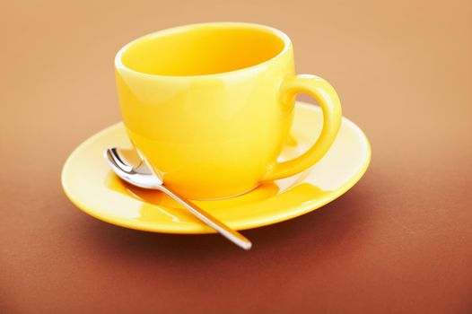 Empty yellow coffee cup over a brown background
