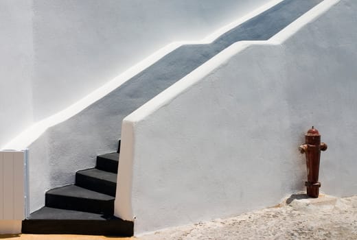 Black stairs on white wall with fire hydrant