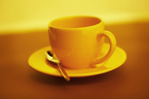 Empty yellow coffee cup over a brown background