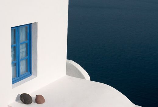 white wall with blue window and stones