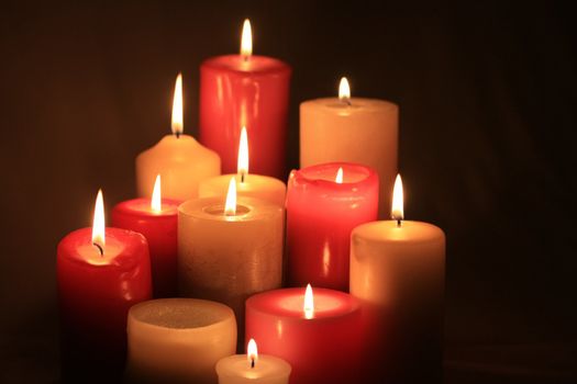 A group of burning candles, different sizes in red and white