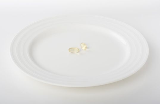 Two diet pills on the white plate